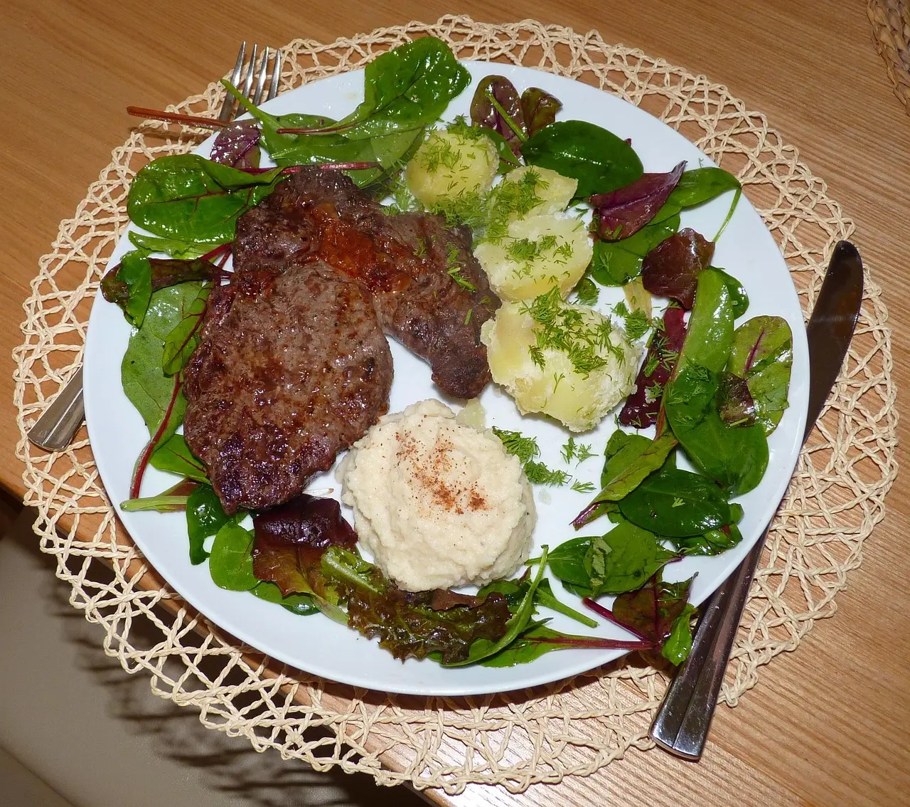 Grilled steak served with potatoes and dressed seasonal leaves